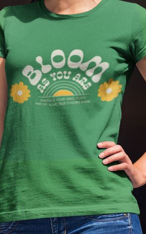 Woman wearing a green t-shirt with 'Bloom as You Are' text and sunflower graphics.