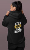 Person wearing a black hoodie with text on the back against a gray background