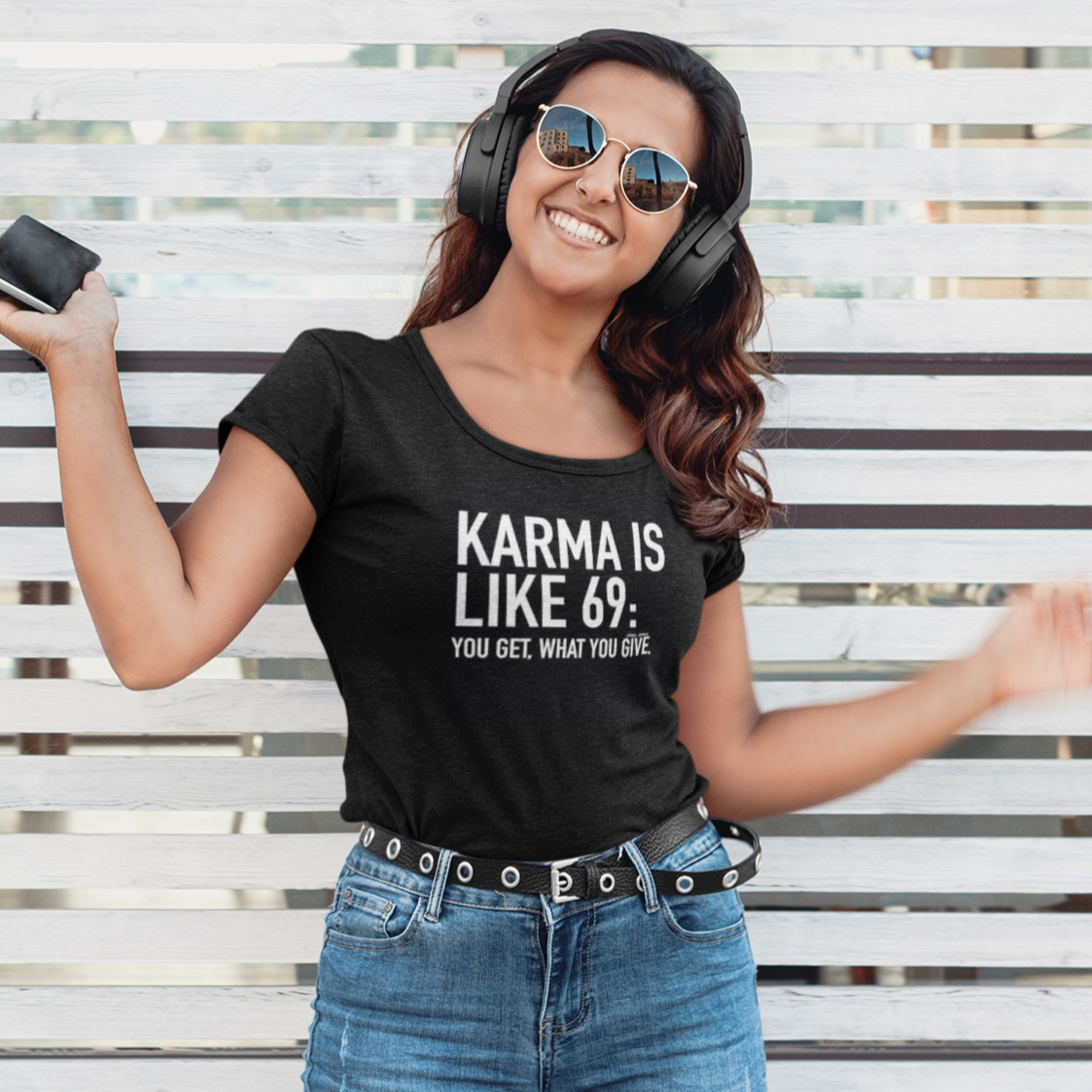 Woman wearing a black t-shirt with text, standing against a white lattice background