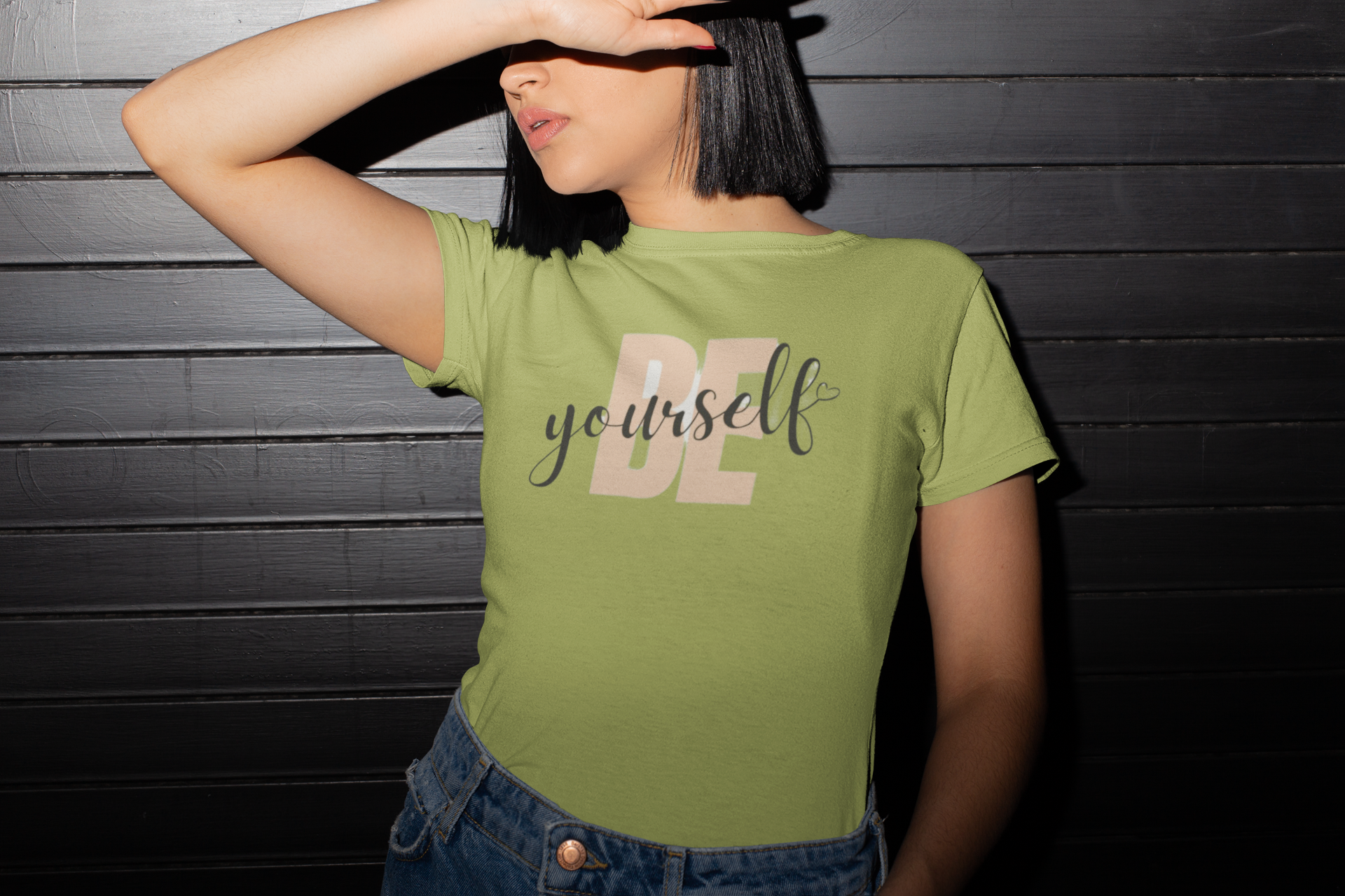 Person wearing a green t-shirt with 'BE yourself' text against a dark wooden background